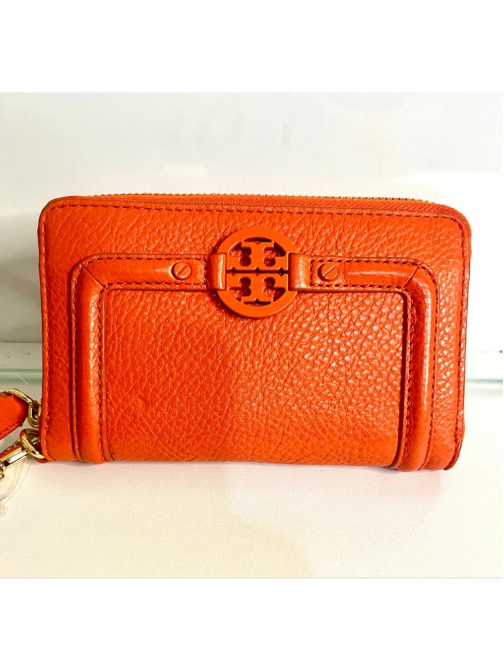 Tory Burch Amanda zip-around wallet featuring vibrant orange pebbled leather.